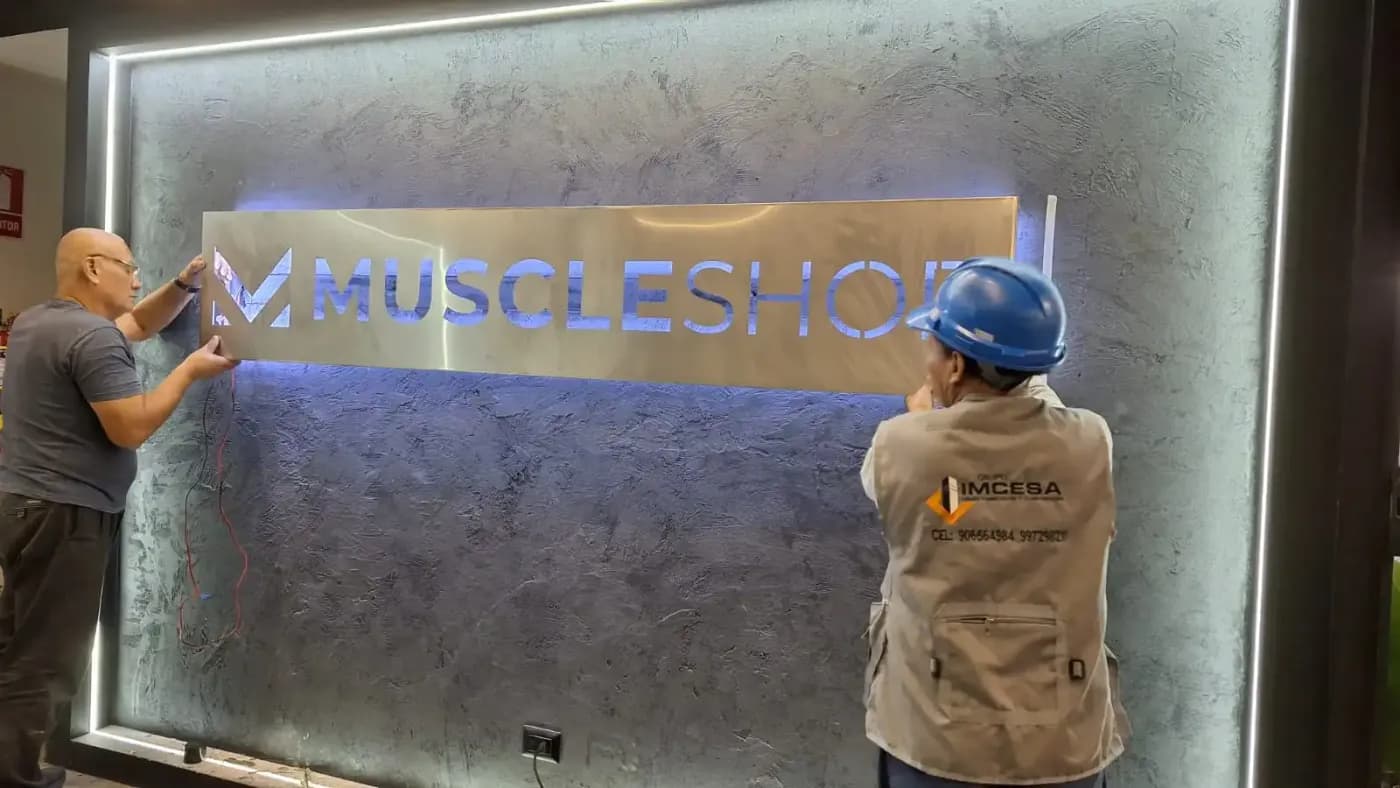 Equipo de IMCESA colocando el panel Muscle Shop con iluminación posterior