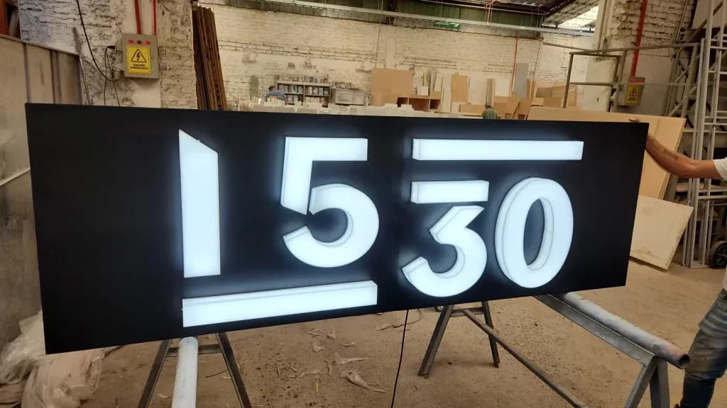 Panel oscuro con números luminosos 1530 en un taller