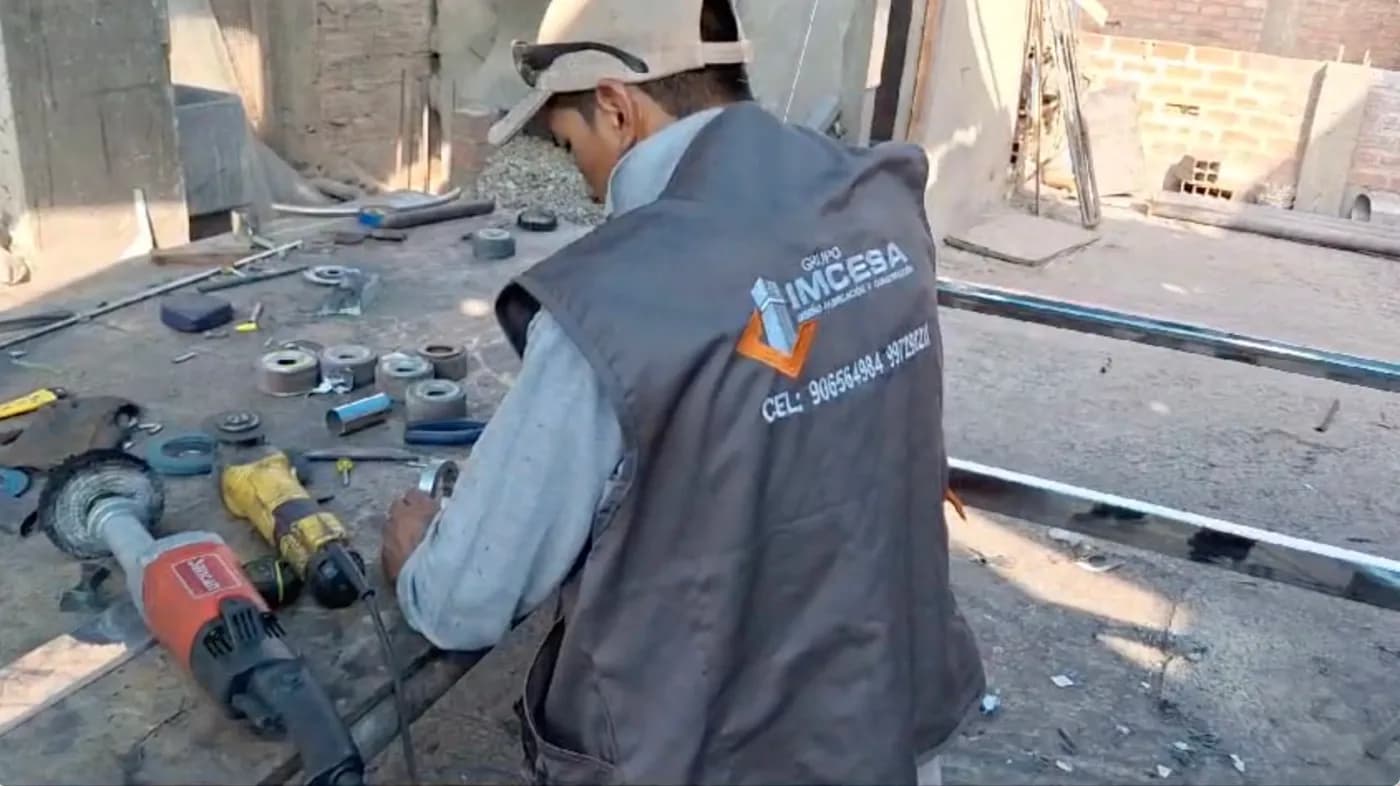 Trabajador con uniforme de IMCESA preparando piezas en una mesa de taller