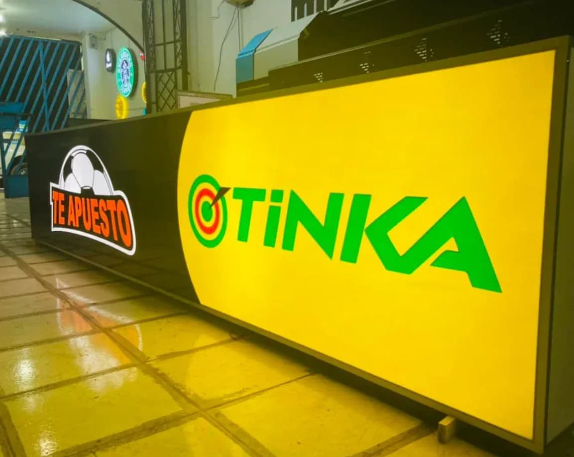 Panel luminoso amarillo con la marca Tinka en un local comercial