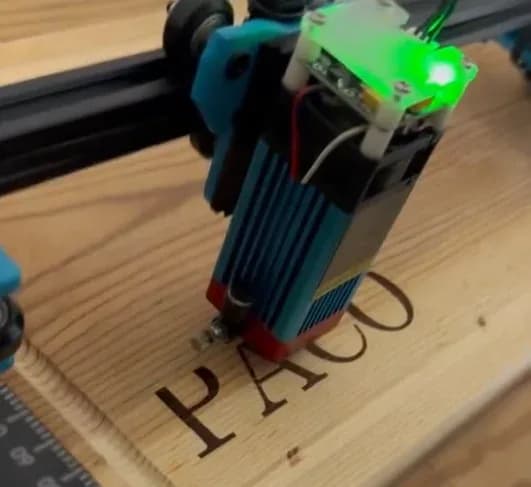Cabezal láser marcando letras sobre una superficie de madera